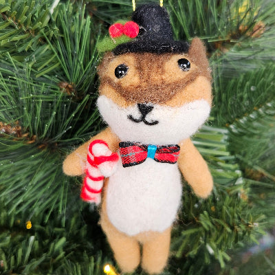 Felt fox ornament with a top hat and candy cane hanging on a Christmas tree.