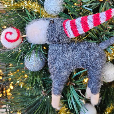 Gray schnauzer ornament with red and white striped hat on a Christmas tree
