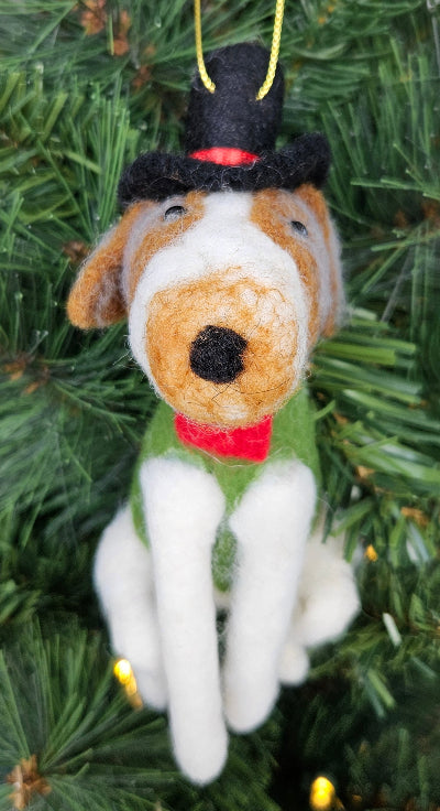 Dog-shaped Christmas ornament on a tree with green leaves and lights.