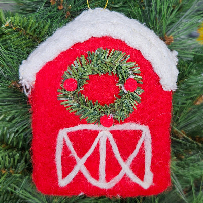 Red barn-shaped Christmas ornament with a green wreath on a tree