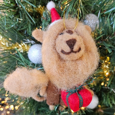 Lion Christmas ornament with red heart and Santa hat on a Christmas tree.