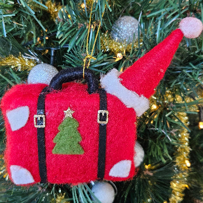 Red suitcase ornament with a green tree design on a Christmas tree.