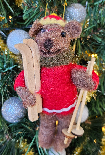 Christmas bear ornament in a red sweater with skis and ski poles on a Christmas tree.