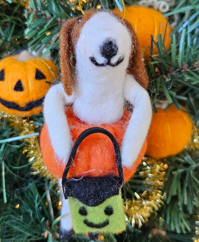 Dog-shaped ornament in an orange bag with a black handle, surrounded by pumpkins and greenery.