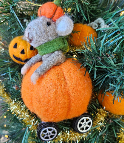 Decorative ornament with a mouse on a pumpkin surrounded by pine branches and pumpkins.