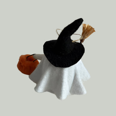 Small decorative Halloween decoration wearing a witch hat with a white dress and orange broom on a light background