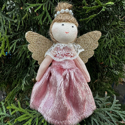 Small angel figurine with gold wings and pink dress on a green leaf background